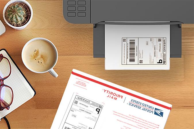 A CNS label waiting in a printer tray beside a Priority Mail envelope.